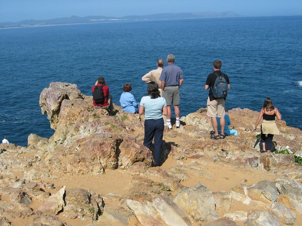 Visitors watch for whales from the rocky cliffs overlooking the ocean in Hermanus along the Garden Route.