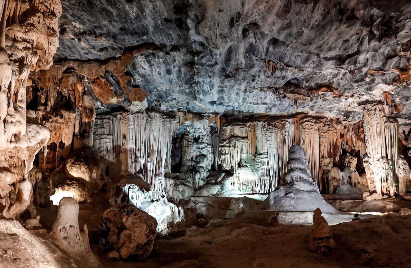 Illuminated dripstone formations and stalagmites fill a spacious underground chamber within the Cango Caves near Oudtshoorn.